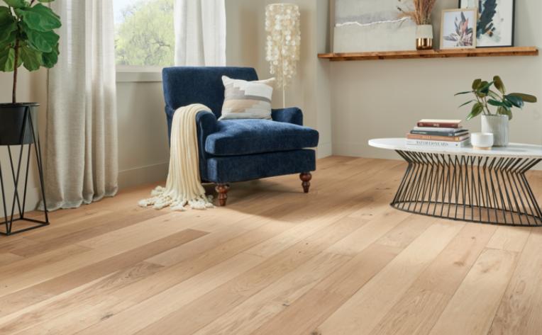 warm toned hardwood flooring in living room with blue antique chair and metal coffee table